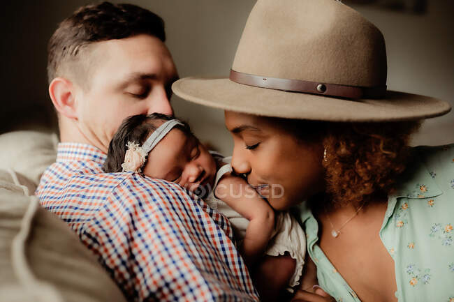 Baby girl sleeping on dad's shoulder, mom kissing baby. — Stock Photo