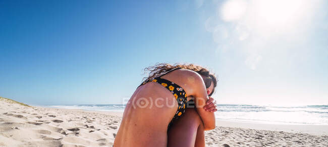 Mulher sentada na praia abraçando-se contra o mar — Fotografia de Stock