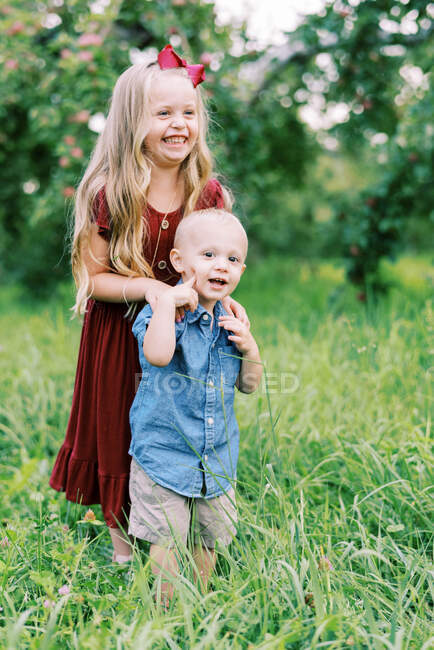 Fratello e sorella in piedi in erba alta in estate a giocare insieme — Foto stock