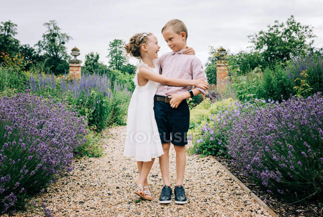 Брати і сестри сміються і грають в красивому квітковому полі влітку — стокове фото
