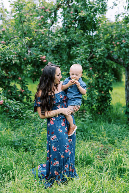 Una giovane madre e suo figlio davanti al melo — Foto stock