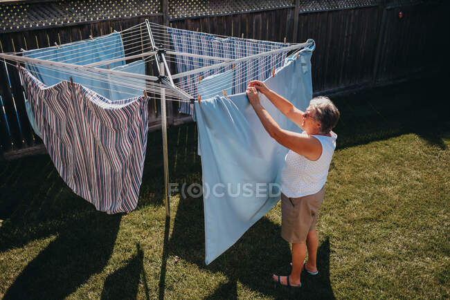 Seniorin hängt Wäsche an Wäscheleine. — Stockfoto