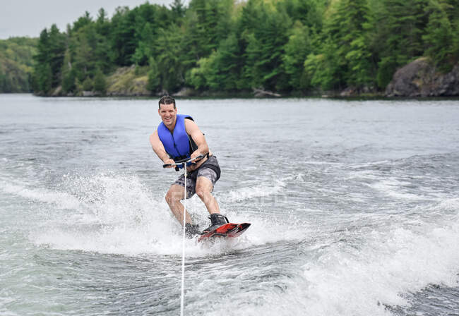 Man wake boarding while being pulled by a boat on a lake — Stock Photo