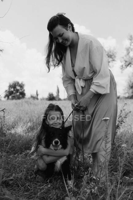 Glückliche Mutter und Mädchen mit Hund im Freien. Pflegekonzept für Haustiere. — Stockfoto