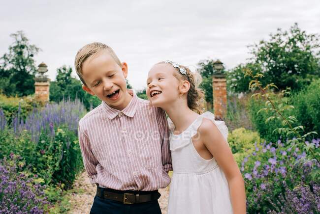 Junge und Mädchen lachen glücklich in einem schönen Blumenfeld — Stockfoto