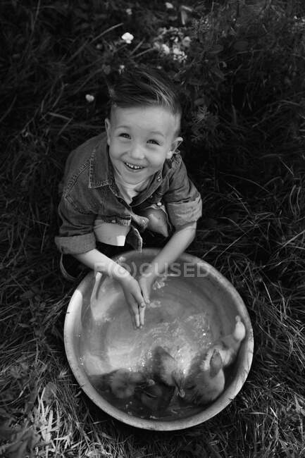 Toddler boy play with the ducklings at the farm — Stock Photo