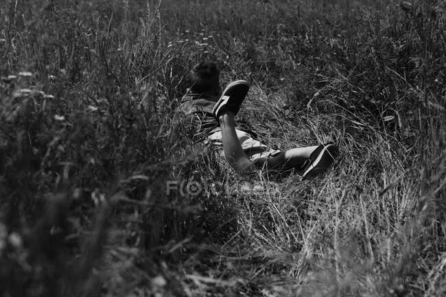 Счастливый мальчик лежит на траве в летнем парке. Симпатичный позитивный ребенок — стоковое фото