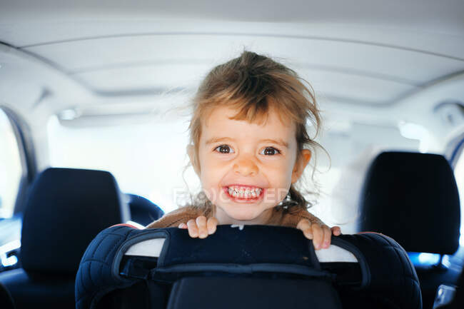 Close-up portrait of a little girl from the trunk of a car. — Stock Photo