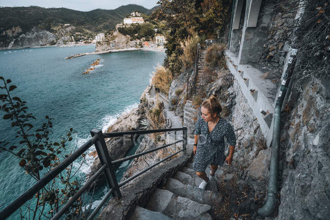 Une jeune femme monte des escaliers sur un sentier côtier à Cinque Terre — Photo de stock