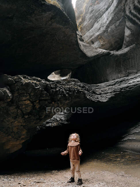 Une petite fille se tient au canyon et lève les yeux. Gorge du Daghestan. — Photo de stock
