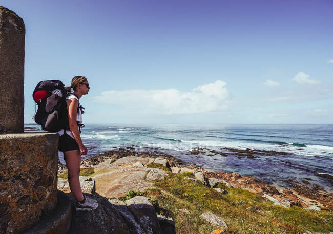 Mulher peregrina em um alto ponto de vista contra praia e mar — Fotografia de Stock