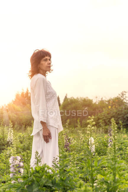 Eine mexikanische Frau trägt ganz in Weiß auf einem Blumenfeld bei Sonnenuntergang — Stockfoto
