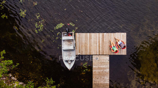 Overhead aerial image of couple sitting on a dock together. — Stock Photo