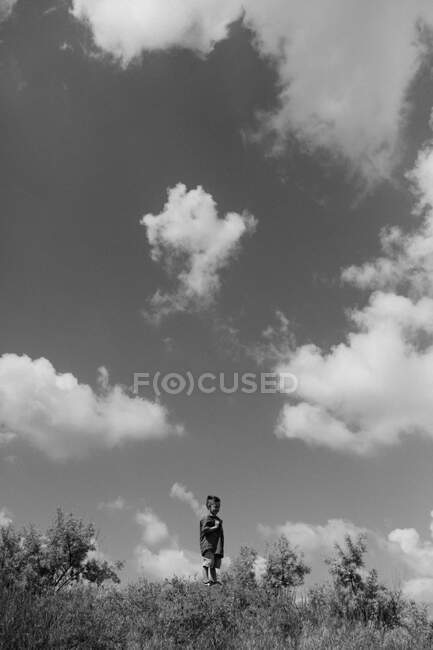 Маленький хлопчик стоїть на горі на тлі неба — стокове фото
