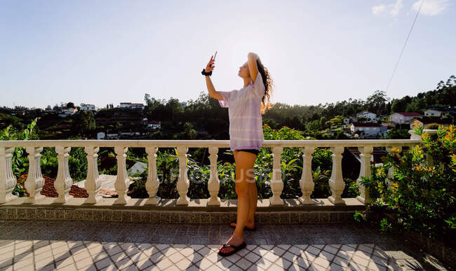 Mulher fazendo uma selfie em um ponto de vista diz o pôr do sol — Fotografia de Stock