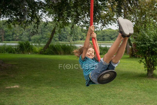 Glücklicher Junge schwingt sich am Wochenendmorgen auf Spielplatz auf Seil — Stockfoto