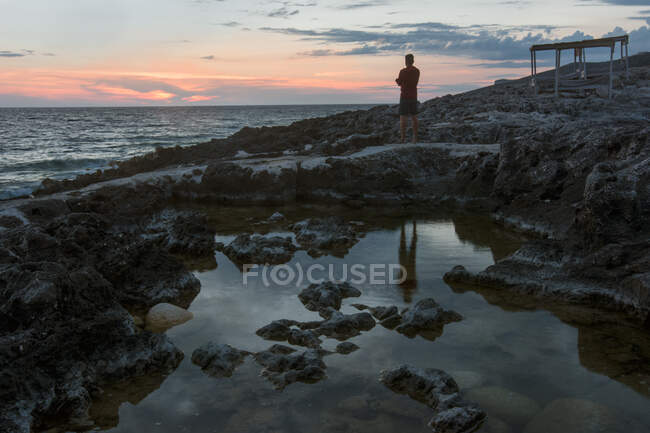 Hombre adulto observando el atardecer sobre Porto Roxa, isla de Zakynthos, - foto de stock