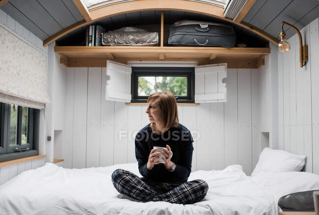 Woman enjoying a coffee sat in a shepherd's hut in the Cotswolds — Stock Photo