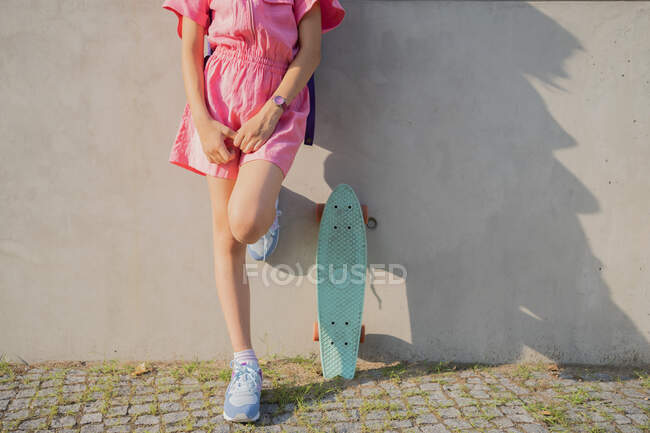Дівчина зі скейтбордом перед сірим тлом — стокове фото