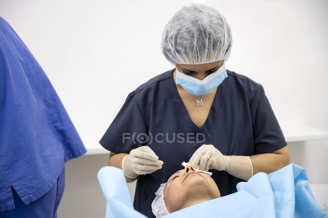 Chirurgiens pratiquant une chirurgie de la paupière à un patient anonyme — Photo de stock