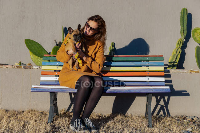 Mulher latina com cão no banco de madeira ao ar livre. — Fotografia de Stock