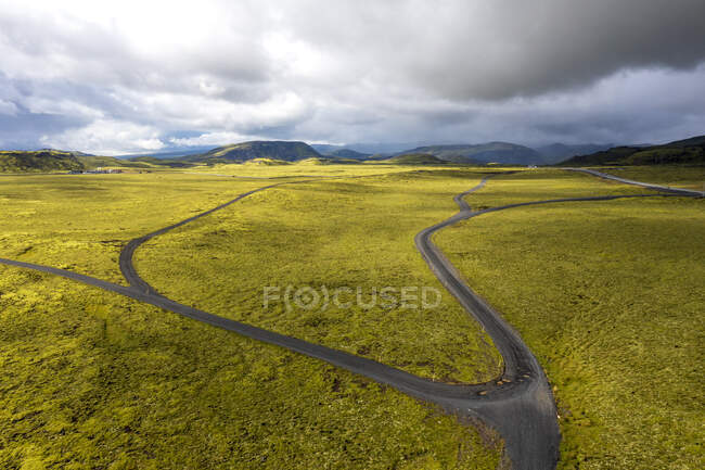 Roads on a landscape covered with moss in dramatic light and stormy clouds. — Stock Photo