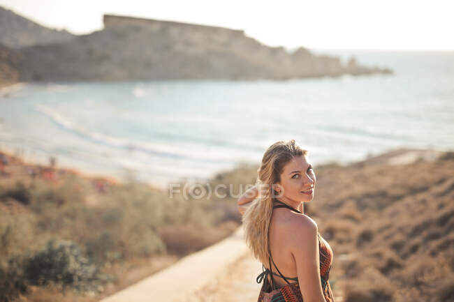 Jeune femme descend les escaliers vers une plage — Photo de stock