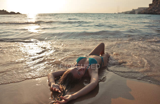 Молода жінка лежить на березі. — стокове фото