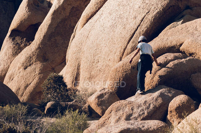 Старший мальчик ходит среди больших камней в пустыне. — стоковое фото