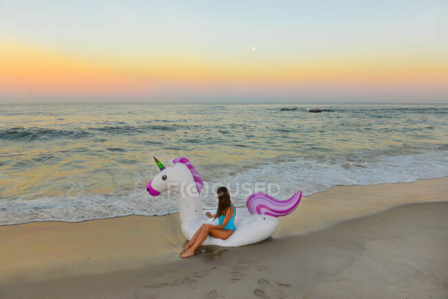 Magisches Mädchen sitzt auf Einhorn-Floß am Strand im Spring Lake, New Jersey — Stockfoto