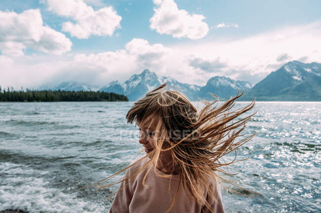 Junges Mädchen wirft ihre Haare an einem sonnigen Tag in der Nähe eines Sees nach draußen — Stockfoto