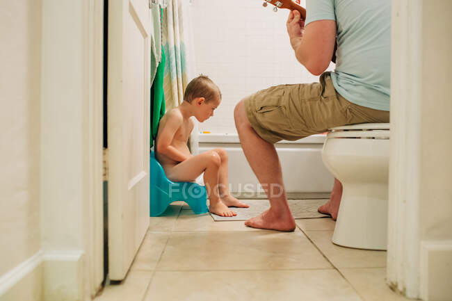 Niño de cuatro años aprendiendo a ir al baño con papá ayudando - foto de stock