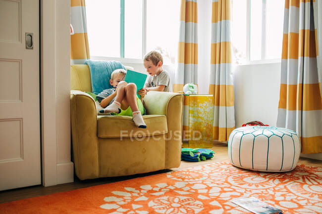 Hermanos caucásicos relajarse en luminosa habitación soleada de vacaciones - foto de stock