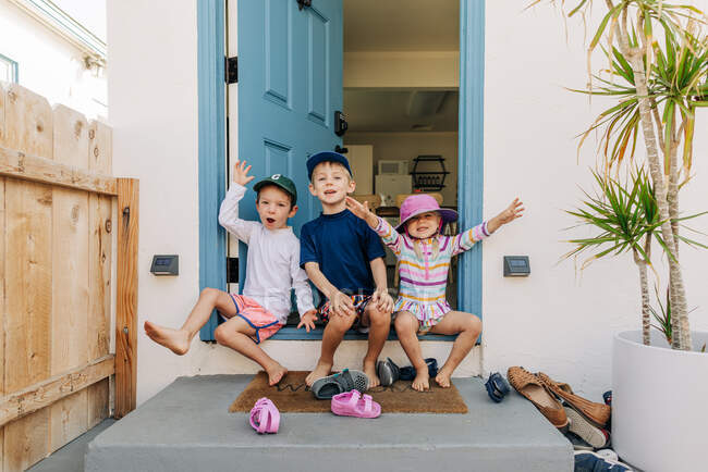 Siblings yell excitedly while sitting on front step of beach house — Stock Photo