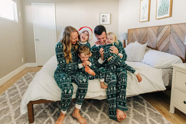 Caucasian family in Christmas pajamas snuggles on bed in Phoenix home — Stock Photo