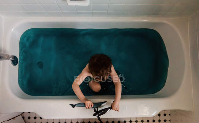С высоты птичьего полета мальчик в ванной играет с китами — стоковое фото