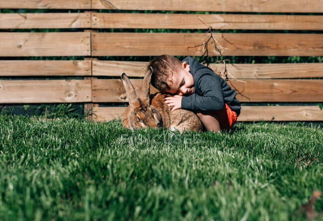 Niño abrazando a un conejo grande - foto de stock