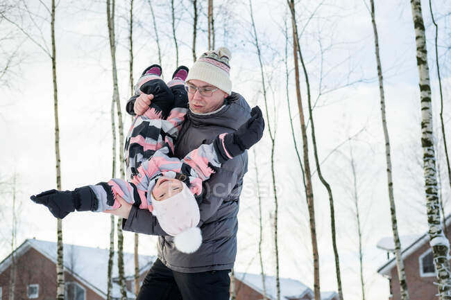O pai com a filha que anda na aldeia de inverno. — Fotografia de Stock