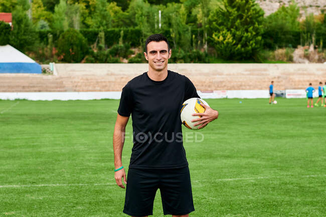 A soccer player with a ball looks at the camera on a football field — Stock Photo