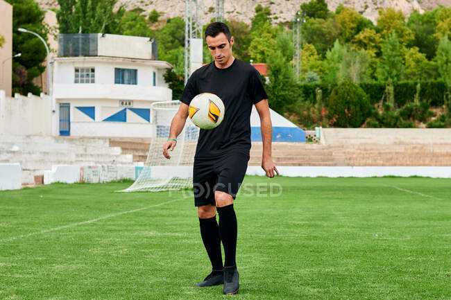 Um jogador de futebol toca uma bola de futebol em um campo de futebol — Fotografia de Stock