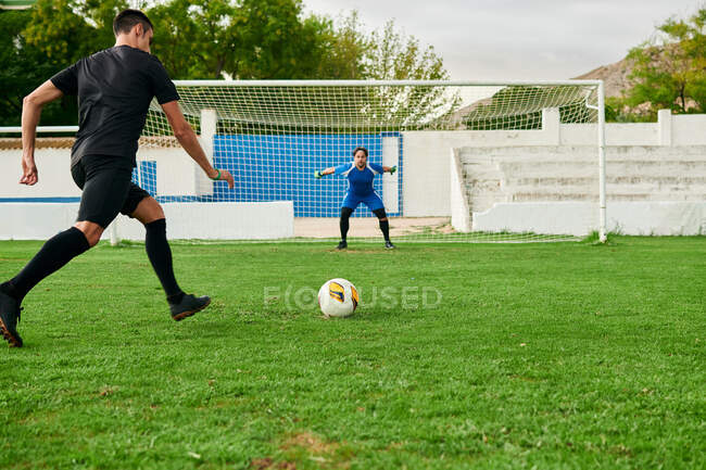 A soccer player takes a penalty kick against a goalkeeper — Stock Photo
