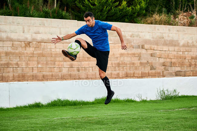 Um jogador de futebol controla a bola em um campo de treinamento de futebol — Fotografia de Stock