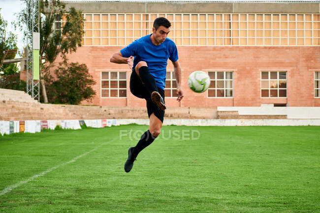 Um jogador de futebol controla a bola em um campo de treinamento de futebol — Fotografia de Stock