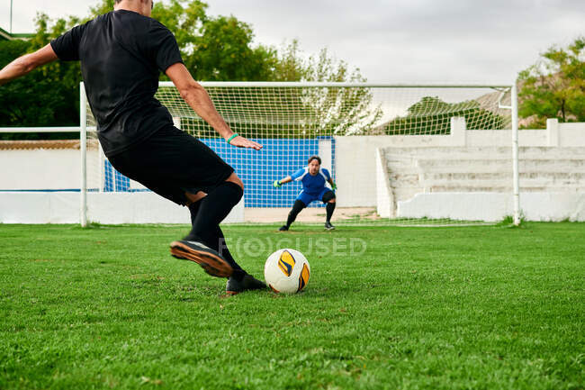 Jogador de futebol dispara uma penalidade contra um goleiro em um campo de futebol — Fotografia de Stock