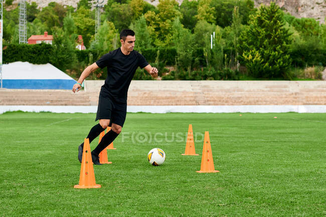 Футболист тренируется на футбольном поле — стоковое фото
