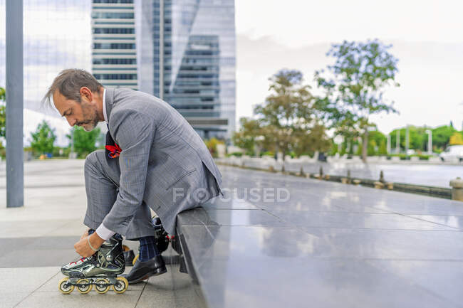 Executive putting on his inline skates — Stock Photo