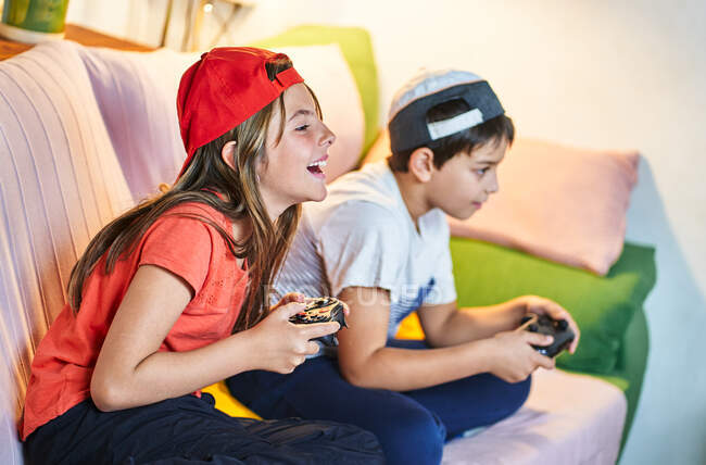 Enfants jouant à des jeux vidéo à la maison — Photo de stock