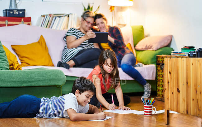 Лесбийская пара со своими детьми веселятся дома — стоковое фото