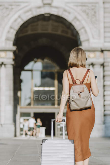 Молода жінка з валізою, що йде містом — стокове фото