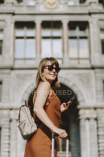 Giovane donna con zaino e smartphone per strada — Foto stock